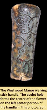 The Westwood Manor walking stick handle.  The eyelet hole forms the center of the flower on the left center portion of the handle in this photograph.